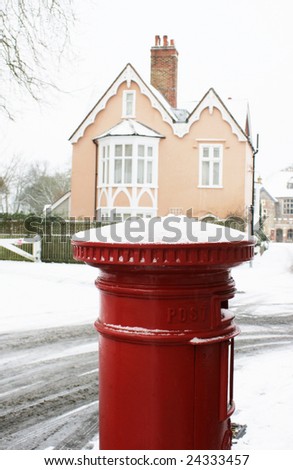 A red pillar box topped with winter snow with a period building to background. located in the Cathedral Close, Salisbury, Wiltshire, England.