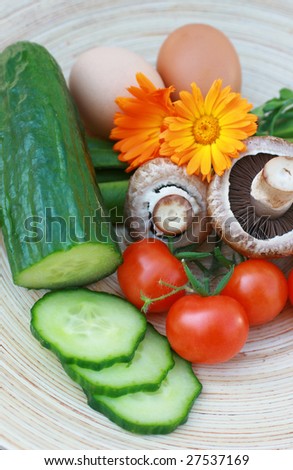Salad ingredients set on a oval wooden platter.Tomato,mushroom,beans,cucumber and eggs. A wooden platter of organically grown ingredients.