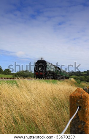 A steam train running on the Swange Railway Line in Dorset, England. Train is rounding a corner through open countryside on its way to its next stop at Swanage.