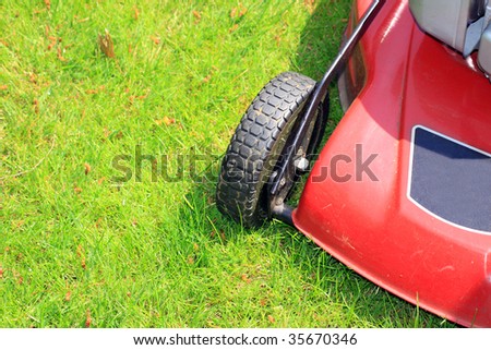 A petrol driven lawn mower with rubber tyres ready to cut a green lawn.
