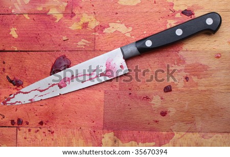 A bloodied wooden butcher\'s block with a blood stained knife.
