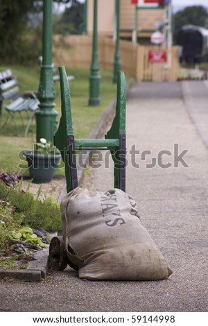 A retro platform trolly holding a hessian sack. Set on the platform at Harmans Cross, part of the Swanage Steam Railway network in Dorset.