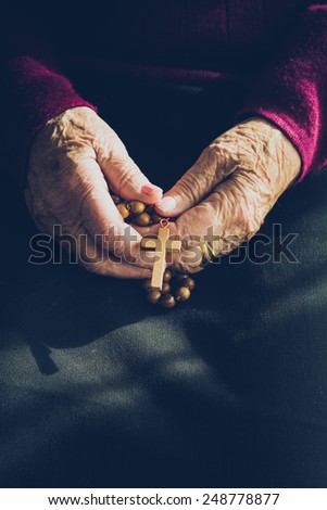 Old woman hands in prayer with a rosary