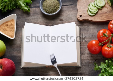 Cooking book on rustic wooden table with vegetables