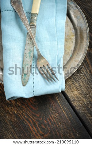 Vintage knife and fork on blue linen napkin over wooden table