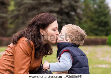 happy mother playing with her son in the park, son kissing his mum