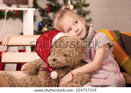 Little girl with a big teddy bear at Christmas