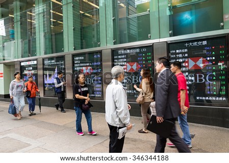 Hong Kong - December 2, 2015: Pedestrians walk past a financial display board in Mong Kok, Hong Kong, China.