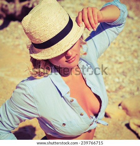 pretty woman in sexy shorts and hat posing at beach. Fashion summer outdoor portrait. Photo with instagram style filters