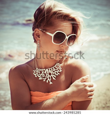 Fashion blonde female in vacation. Posing with cute summer style, pare on bikini, sunglasses and big white necklace. Photo with instagram style filters