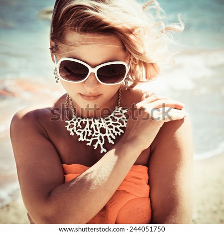 Fashion blonde female in vacation. Posing with cute summer style, pare on bikini, sunglasses and big white necklace. Photo with instagram style filters