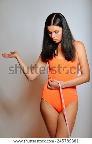 Fit woman measuring her waist. Slim girl with centimeter isolated on white