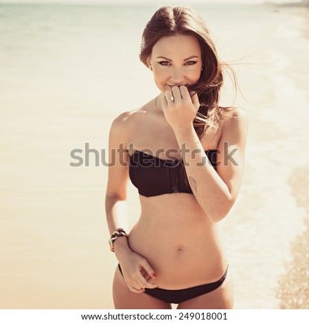 Woman with beautiful body on a tropical beach. beautiful young woman in a black bathing suit relaxing on the beach. Hipster style
