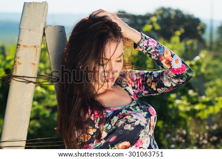 Sexy beautiful brunette woman with slim tanned body, long developing hair, clean face posing outdoor enjoys fine warm summer weather