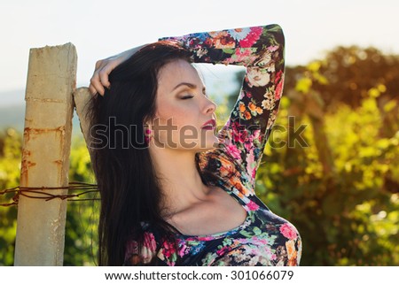 Sexy beautiful attractive brunette woman with slim tanned body, long developing hair, clean face posing outdoor enjoys fine warm summer weather