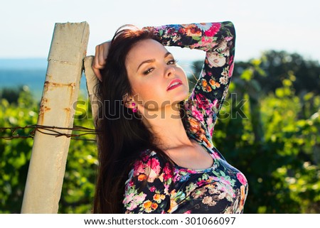 Sexy beautiful attractive brunette woman with slim tanned body, long developing hair, clean face posing outdoor enjoys fine warm summer weather
