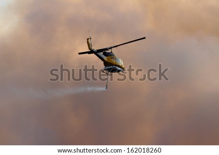 Ningi, Australia - November 9 : Waterbomber Helicopter With Full Load Heading To Fire Front Into Clouds Of Smoke November 9, 2013 In Ningi, Australia