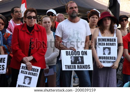 BRISBANE, AUSTRALIA - JUNE 22 : Unidentified protesters holding anti liberal government and reza berati remembrance signs  attending World Refugee Rally June 22, 2014 in Brisbane, Australia