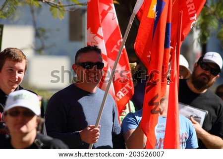 BRISBANE, AUSTRALIA - JULY 06 : Unidentified protesters with NUW union flags at Bust The Budget anti liberal government Rally July 06, 2014 in Brisbane, Australia