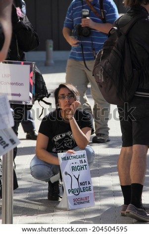 BRISBANE, AUSTRALIA - JULY 12 : Unidentified protester with anti Medicare policy sign outside Liberal National Party national conference July 12, 2014 in Brisbane, Australia
