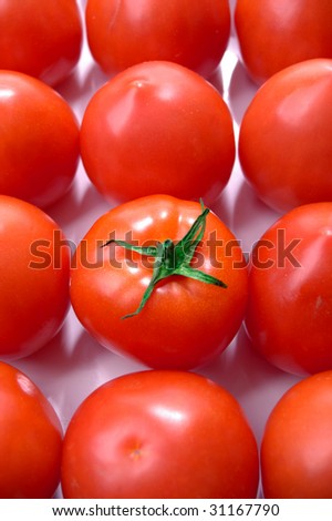 Display of a group of market fresh tomatoes with odd one out