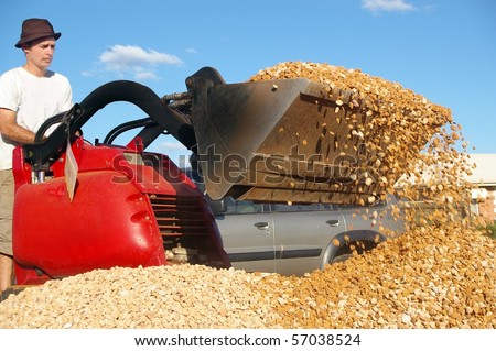 man operating small earth moving machine on gravel