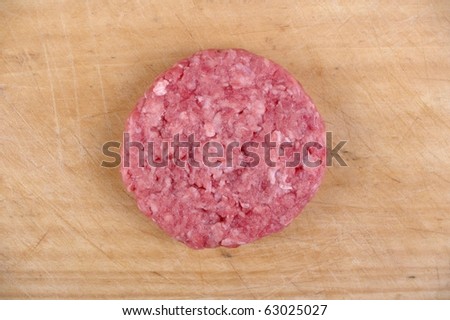organic minced meat burger patty on wooden chopping board