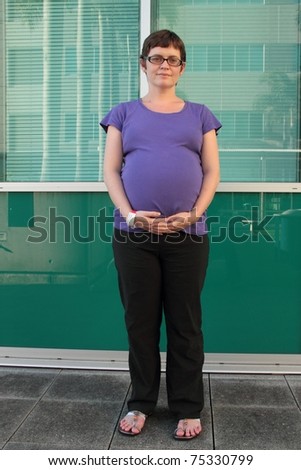 Pregnant woman with hospital admission tag outdoors in the grungy rbh grounds