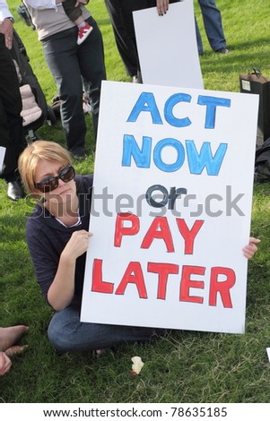 BRISBANE, AUSTRALIA - JUNE 6 : Woman with act now or pay later anti pollution sign at say Yes to carbon tax World Environment Day protest 6, 2011 in Brisbane, Australia