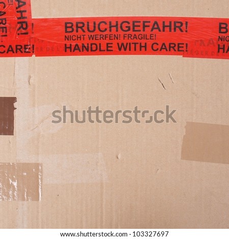 Fragile packet parcel with warning label in English and German - Handle with care, Bruchgefahr