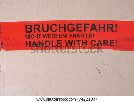 Fragile packet parcel with warning label in English and German - Handle with care, Bruchgefahr