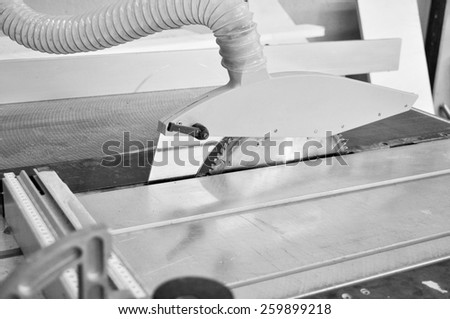 A table saw sawbench tool circular saw blade mounted on an arbor driven by an electric motor in black and white