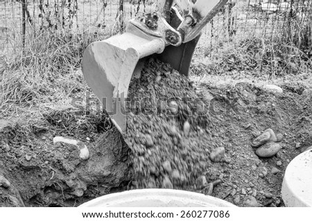 Excavator mechanical shovel digger digging a hole in the ground in black and white
