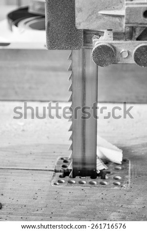 Bandsaw power tool which uses a blade consisting of a continuous band of metal with teeth along one edge to cut in black and white