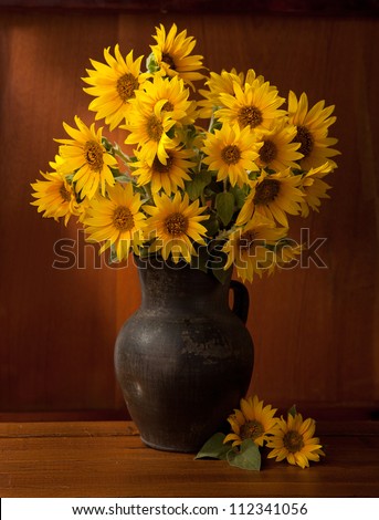 Still life. Beautiful Sunflowers in  old clay pot against a wooden wall