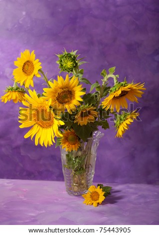 Sunflowers in a transparent glass vase on abstract background