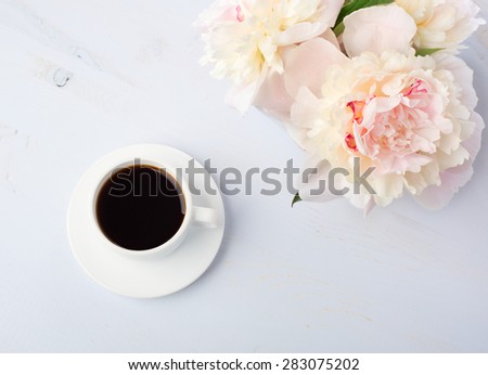 Still life with cup of coffee and flowers (peonies) on light blue wooden table.