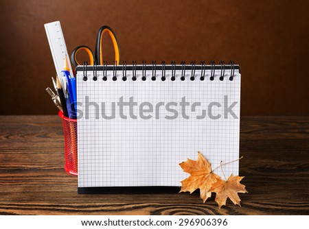 School equipment with pencils, notebook and dry autumn leaves  on wooden table . Back to school or Teachers\' Day -  concept.