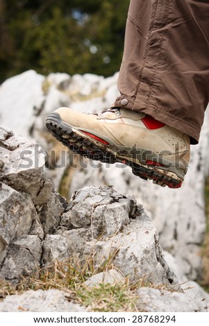 White Hiking shoe is just about to step on a rock on a mountain