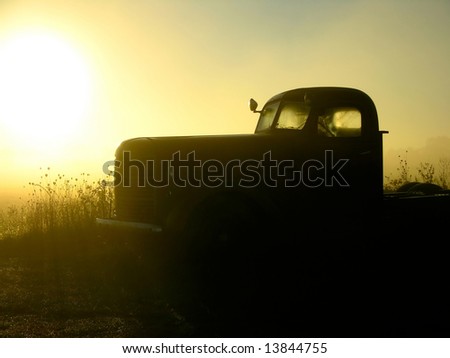 An old truck sits in the early morning mist.