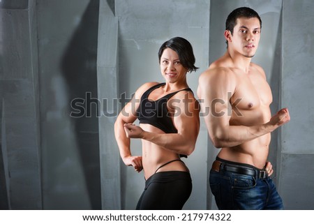 Male and female bodybuilders. Fitness, sport, training, gym and lifestyle concept - two smiling people standing in the gym. The idea of article about sport and fitness.
