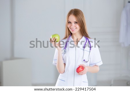 Doctor holding a green and red apples. Concept of healthy food. Smiling medical woman doctor at Hospital.