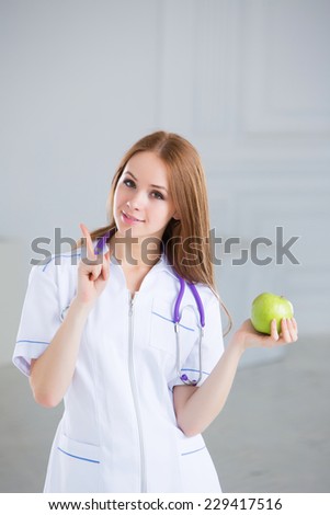 Doctor holding a green apple. Concept of healthy food. Smiling medical woman doctor at Hospital.