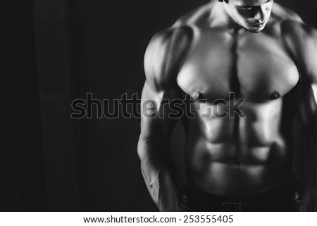 Muscular male bodybuilder, on a dark background. black and white photo