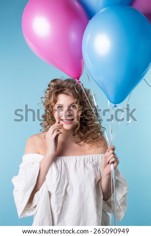 Woman with curly hair holding balloons on a blue background