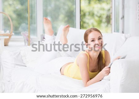 Young beautiful woman lying on the couch with touchpad