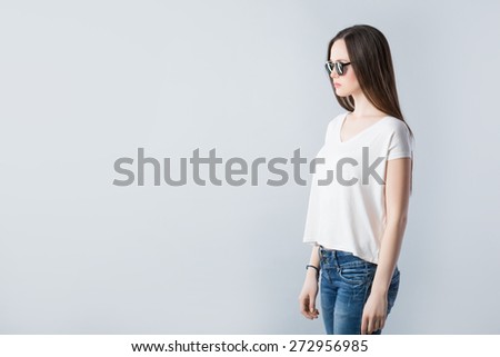 Sexy girl. Indoor fashion portrait of young beautiful woman in t-shirt, jeans and sunglasses