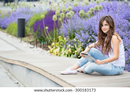 Young beautiful woman in the park with gadgets in a park