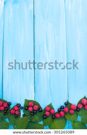 Fresh berries. Raspberries and currants on a blue wooden background.