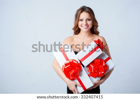 Portrait young happy woman with white boxes with red bows in hands.